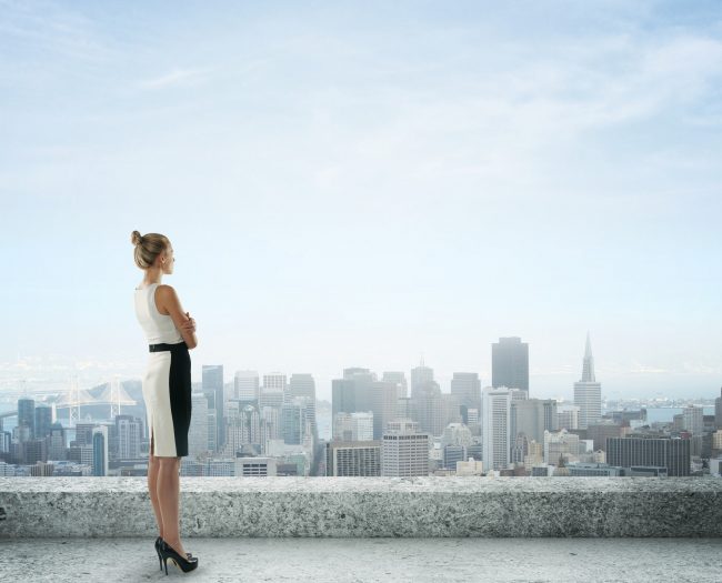 businesswoman on roof looking at city